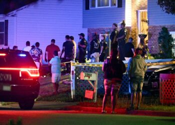 Police stand among a crowd outside a home where multiple people were shot in Annapolis, Md., on June 11, 2023.