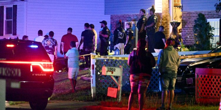 Police stand among a crowd outside a home where multiple people were shot in Annapolis, Md., on June 11, 2023.
