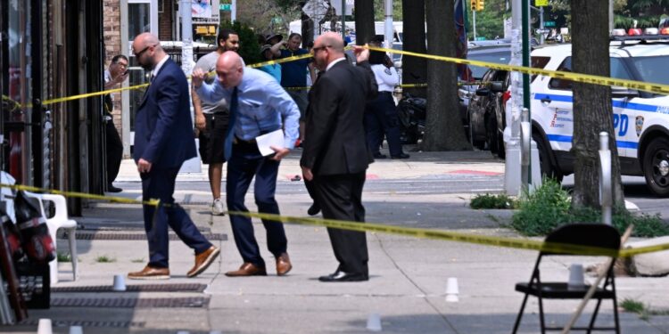 Detectives duck under crime scene tape on a sidewalk at the scene of shooting