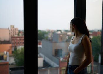 The woman looking out a window with her face blurred.