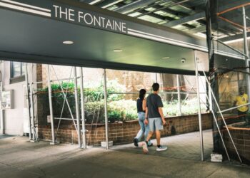 A couple walking up to the entrance of The Fontaine co-op building on the Upper East Side of Manhattan.