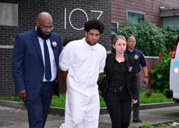 Police walking Abreu out of the 107th Precinct.