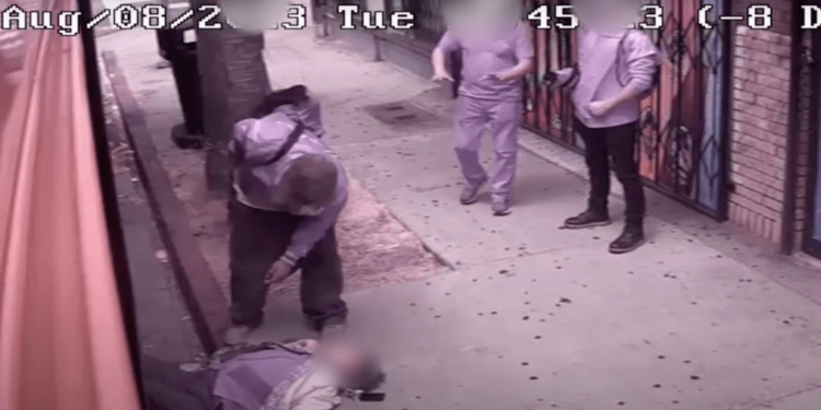 A man in a beanie and a New York Yankees jacket then steps off the bus and steps over the woman.