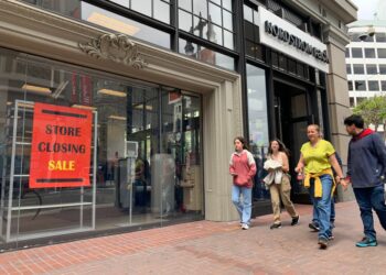 A family walks past a Nordstrom with a "Store Closing Sale" on its window