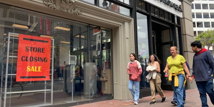 A family walks past a Nordstrom with a "Store Closing Sale" on its window
