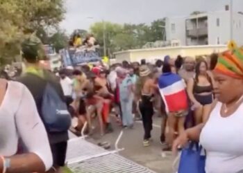 A crowd at a parade with barriers knocked down.