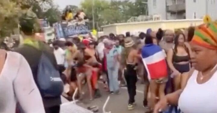 A crowd at a parade with barriers knocked down.