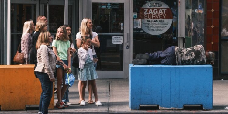 Tourists next to a sleeping homeless man in Times Square
