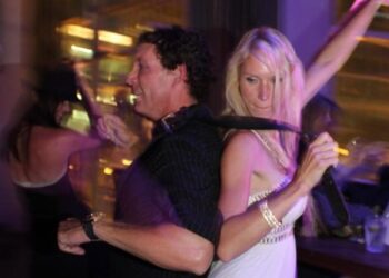 Tatyana Remley dancing with her husband Mark. She has a belt around his neck and is holding it.