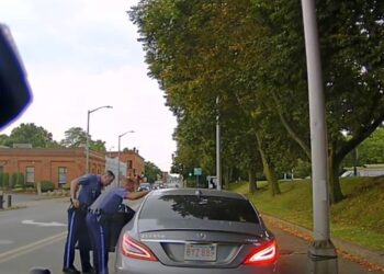 Two officers looking into Derek Lobo's car.