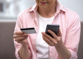 Senior female entering credit card number on smartphone.