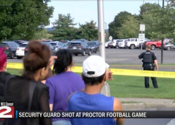 People look at a police investigation from behind crime tape.