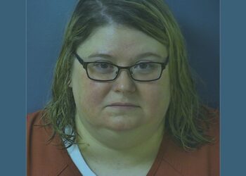 Mugshot of Heather Pressdee, wearing glasses and orange clothes.