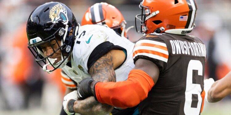 Cleveland, Ohio, USA; Jacksonville Jaguars tight end Evan Engram (17) is tackled by Cleveland Browns linebacker Jeremiah Owusu-Koramoah (6) as he runs the ball during the fourth quarter at Cleveland Browns Stadium.