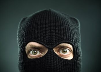 Closeup of a man's face covered in a black ski mask.