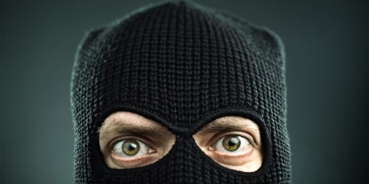 Closeup of a man's face covered in a black ski mask.