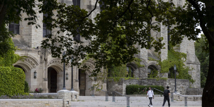 Two students walk past a university building.