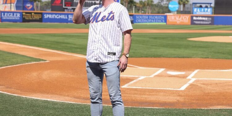 Jonathan Wibben singing into a microphone on a baseball field.