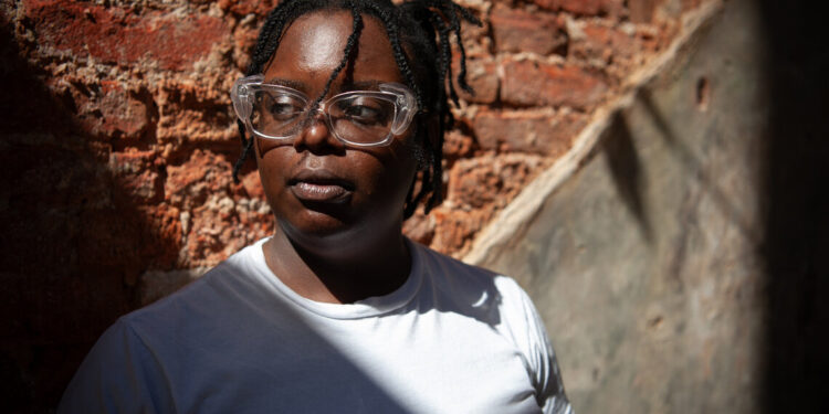 A Black woman with glasses looks off camera.