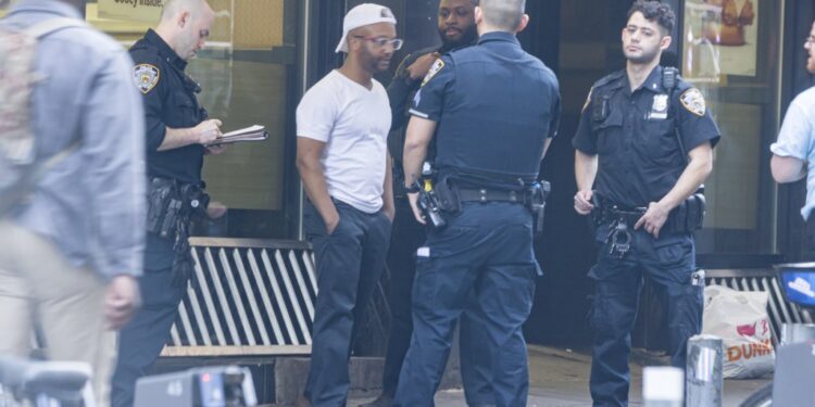 A group of men outside Burger King with one receiving a summons from NYPD.