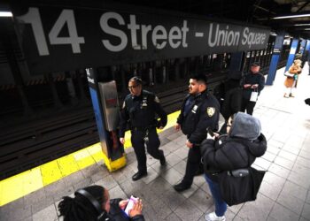NYPD officers patrol Union Square subway station platform.