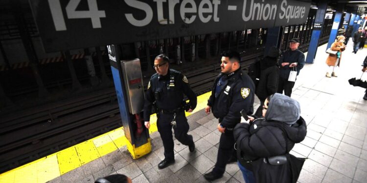NYPD officers patrol Union Square subway station platform.