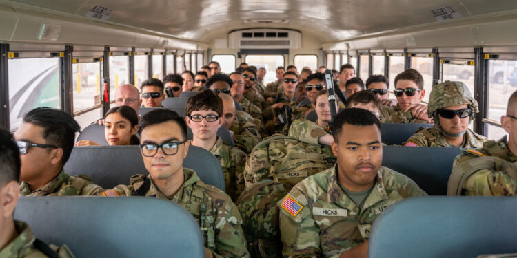 Texas Tactical Border Force guardsmen dressed in uniforms sit on a bus at the airport in El Paso, Texas.