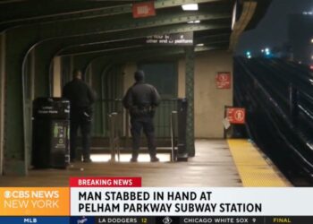 A man standing in a subway station platform at night.