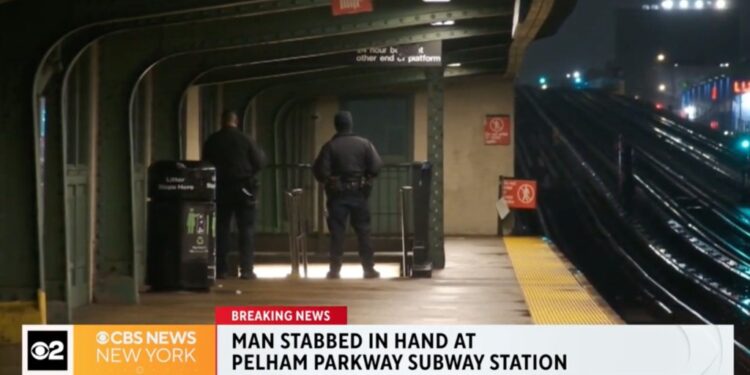 A man standing in a subway station platform at night.