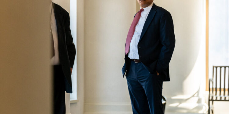 Attorney Bill Beck, a Black man wearing a dark suit and glasses, stands in the halls of the Juvenile Justice Center in Cleveland.