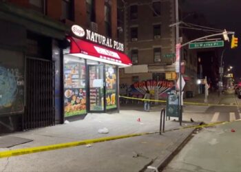 A yellow police tape surrounds a storefront with a sign.