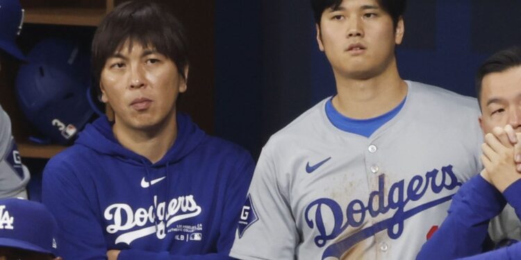 Shohei Ohtani (R) of the Los Angeles Dodgers and his interpreter Ippei Mizuhara watch the MLB season-opening game against the San Diego Padres from the dugout at Seoul's Gocheok Sky Dome on March 20, 2024.