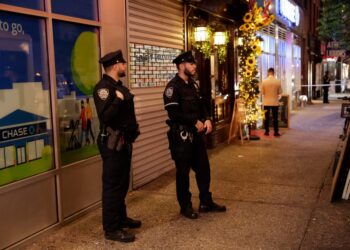 NYPD officers stand near the scene where a woman was stabbed at a Thai Grocery store in Manhattan on Tuesday night.