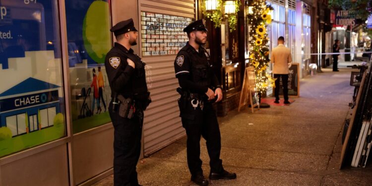 NYPD officers stand near the scene where a woman was stabbed at a Thai Grocery store in Manhattan on Tuesday night.