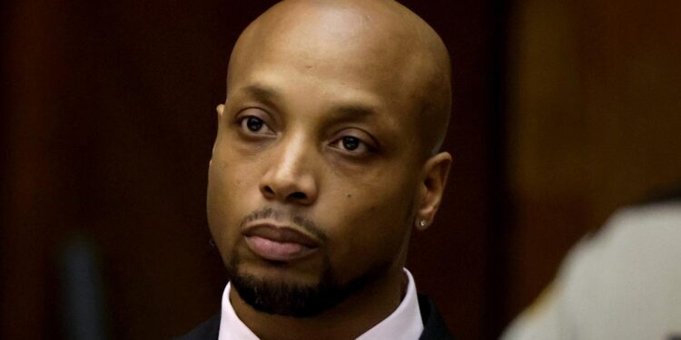 Lafeal Lawshea, a Black man wearing a black suit and pink shirt, in a courtroom.