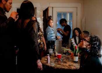 A photo of a group of Black friends and family members around a table inside a home.