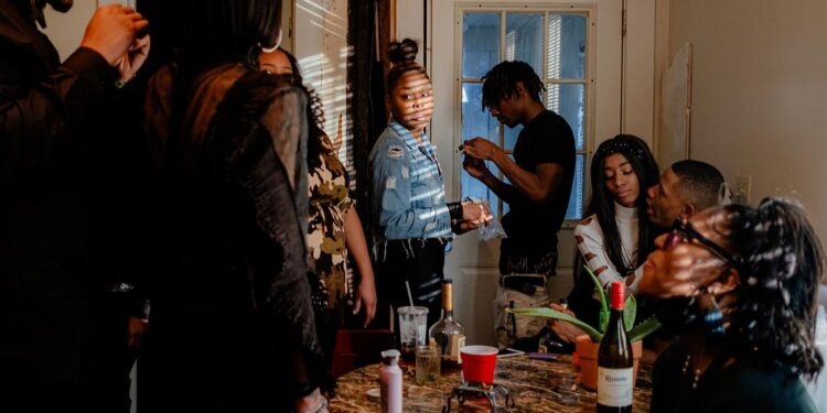 A photo of a group of Black friends and family members around a table inside a home.
