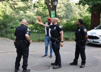 NYPD Central Park Precinct officers conversing with victim Johnny Edwards about a robbery at gunpoint near a lake in the park