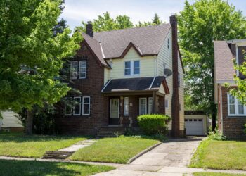 A photo shows a brick home with a grass lawn.