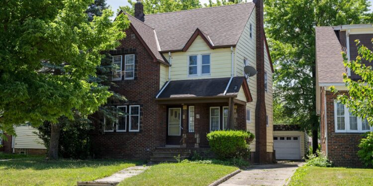 A photo shows a brick home with a grass lawn.
