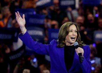 U.S. Vice President Kamala Harris in a blue suit, speaking into a microphone at her rally in Milwaukee, Wisconsin, for a live broadcast to the Democratic National Convention