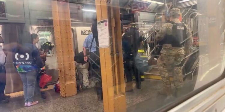 photo of EMTs helping victim at train station