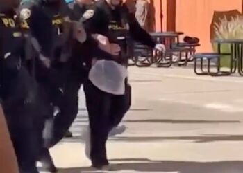 School district police carrying a bound student after a physical altercation.