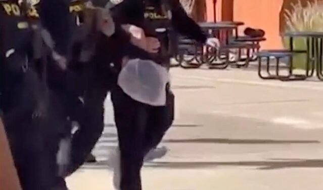 School district police carrying a bound student after a physical altercation.