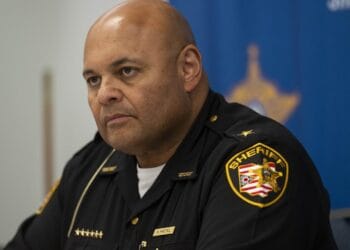 Cuyahoga County Sheriff Harold Pretel, a bald man with medium-toned skin, wears a black uniform with a sheriff’s patch on his left shoulder.