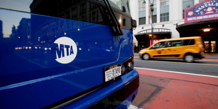 NEW YORK, NEW YORK - DECEMBER 2: A taxi drives near an MTA bus on December 2, 2022 in New York City. NYC Metropolitan Transportation Authority has proposed a 5.5 percent fare hike next year, this would push subway and bus fares to $2.90 in 2023.