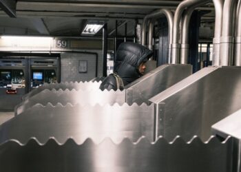 Commuters passing by a serrated metal siding installed on turnstiles at the 59th Street/Lexington Avenue subway station to prevent fare evasion