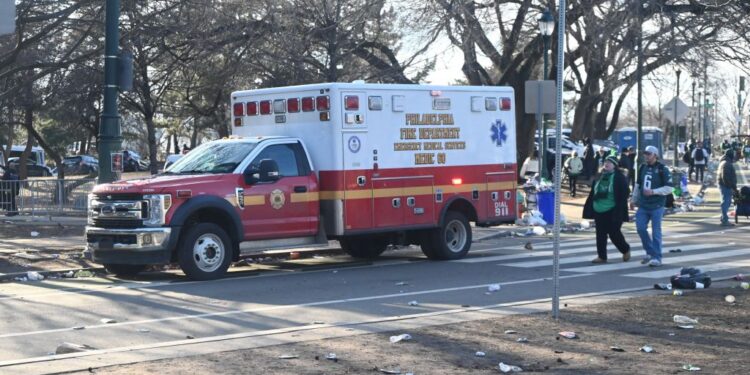 Philadelphia Eagles Super Bowl Parade showing a red and white ambulance on North 24th Street, celebrities Seanan McGuire and Ernie Els in the background.