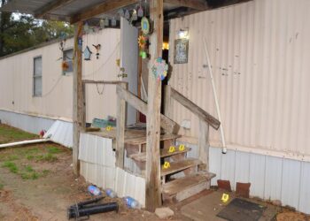 A photo shows the back entrance of a home with hanging decorations and bullet holes. Numbered yellow evidence markers are placed around the stairs leading up to the front door.