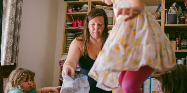 Susan Horton, a White woman wearing a black tank top, arranges her children’s toys on top of a table.
